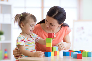 Mutter und Tochter spielen mit Holzklötzen