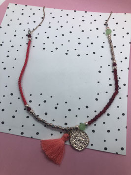 Een goudkleurige ketting met zalmroze kwast