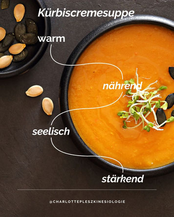 Kürbiscremesuppe in schwarzer Schale, dekoriert mit Keimlingen und Kürbiskernen. Text im Bild: Kürbiscremesuppe – warm, nährend, seelisch, stärkend. Symbolbild für ganzheitliche, herbstliche Ernährung und seelische Nahrung
