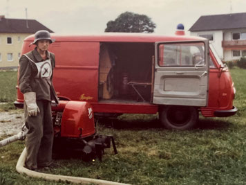 Maschinist vor dem ersten Tragkraftspritzenfahrzeug (TSF) und der zweiten Tragkraftspritze (TS) bei der Leistungsprüfung im Jahr 1981.