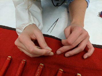 Hands of a European trained museum conservator working on stabilizing a fabric, after negotiations with the knowledge holder of the source community concluded that the treatment was necessary to honor the object. © Diana Gabler, 2017.