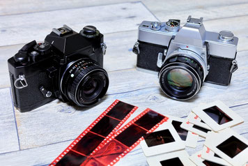 一眼レフカメラと、テーブルに並べられたポジフィルム・スライド