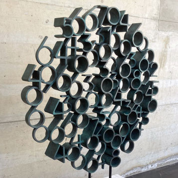 Tobia by Paolo Grassi, large circular bronze sculpture with protruding cylindrical numeric elements