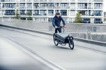 Mann fährt mit seinem Load 75 Lasten e-Bike von Riese & Müller durch die Stadt