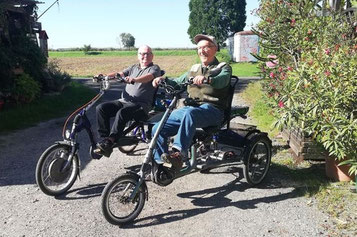 Zwei Kunden fahren auf ihren Dreirädern übers Feld