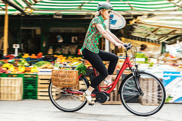 Frau mit e-Bike und Einkäufen Probefahrt