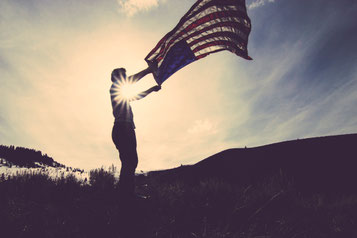 Mann mit amerikanischer Flagge in Sonnenuntergang