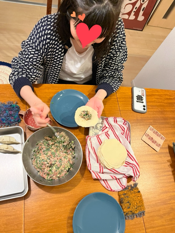 女性が笑顔で餃子を包む