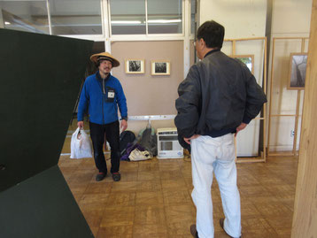 笠を被って、その由来などを来客に説明している岳さん