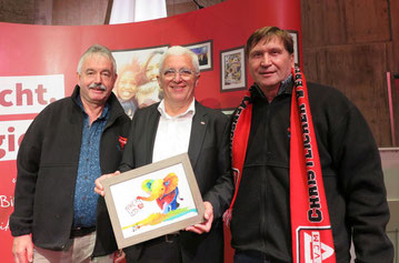 Michael Kühn (links) und Manfred Wille (rechts) übergeben ein farbenfrohes Bild mit einem Elefanten, der im Rüssel das Logok zum 175-jährigen Jubiläum trägt, an Karl-Heinz Stengel