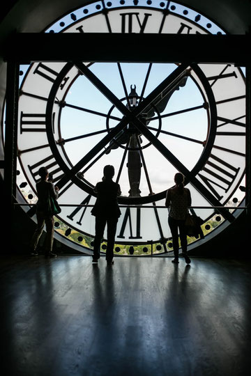 Silhouettes devant une immense horloge évoquant le temps