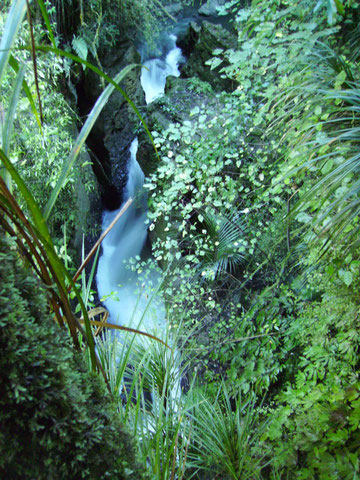 Blick in das felsige grüne Tal auf einen reißenden Wasserfall