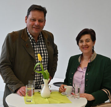 Zwei Personen posieren lächelnd bei einem Stehtisch