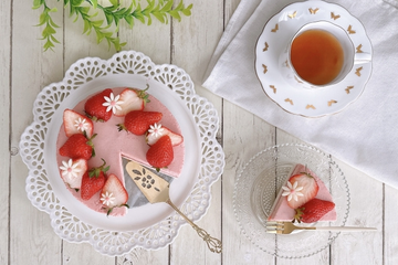 いちごムースのホールケーキがガラスのお皿に取り分けられている。紅茶の入ったカップ&ソーサ。