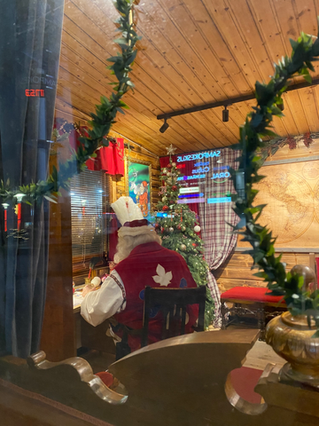 Babbo Natale, di spalle, intento a scrivere una lettera, nell'ufficio postale del centro di Rovaniemi, in Lapponia