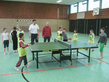 Günter Donath (roter Pullover) und Ingo Sillge (weißes Hemd) staunen über die Tischtenniskünste der Westhagener Kinder