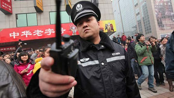 A police officer disperses members of the public, most of them onlookers, and media outside a McDonald's after internet social networks called for a "Jasmine Revolution" protest in Beijing. (How Hwee Young / EPA / February 20, 2011)