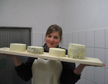 Eine Frau präsentiert vier verschiedene Käsesorten auf einem Brett