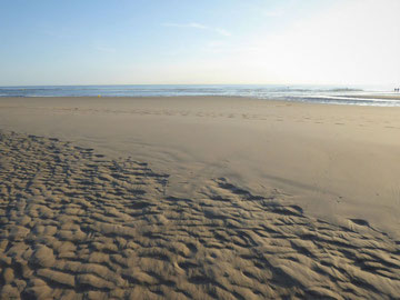 Strand in Nordfrankreich mit Fußspuren im Sand, das Meer weit im Hintergrund