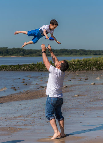 Familienfotos im Freien am Strand - Papa wirft Sohn in die Luft