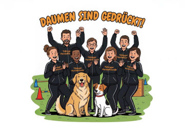 Gruppe in schwarzen Trainingsanzügen mit Aufschrift 'Tübinger Hundefreunde' steht auf Wiese, hebt Arme, zwei Hunde sitzen vorne, Text 'DAUMEN SIND GEDRÜCKT!' darüber.