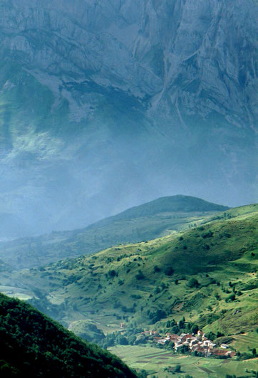 In Spain's Picos de Europa, a tiny village huddles below a looming cliff face.