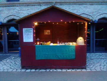 Der Stand auf dem Weihnachtsmarkt mit duftenden Bienenwachskerzen, leckerem Bio-Honig und Bio-Met sowie Bio-Honigbonbons. Wir haben ihn schön gestaltet und eine Kerze angezündet. Bienenkorb stand auch da.