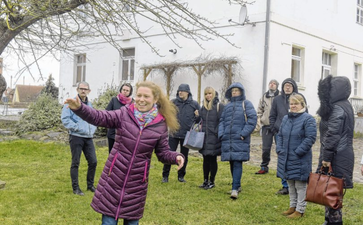 Freudestrahlend stellt Frau Friedrich einer Gruppe von Menschen das Projekt vor