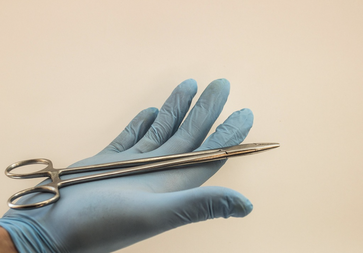 Chirurg mit Handschuh und Werkzeug in der Hand