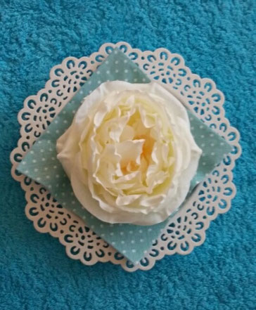 Schöne-weisse-Blume-auf-türkisgepunkteter-Serviette-in-weisser-Schale