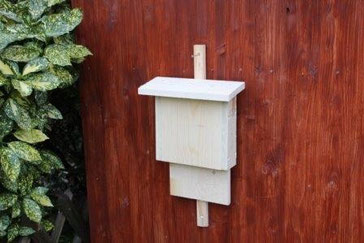 Fledermauskasten aus hellem Holz an einer Holzwand
