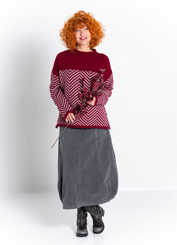 Model mit rot-eeiss gemustertem Pullover aus der Kollektion Jordis und langem Cordrock in anthrazit.