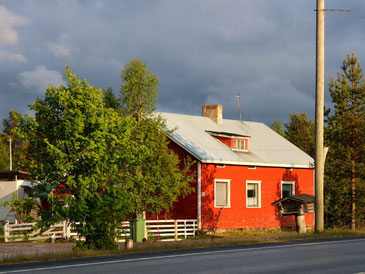 Sehenswürdigkeiten Finnland: Eine typische Holzhütte mit roter Fassade und weiß bemalten Rähmen steht an der Hauptstraße von Vuotso, der südlichsten Sámi-Siedlung Finnlands.