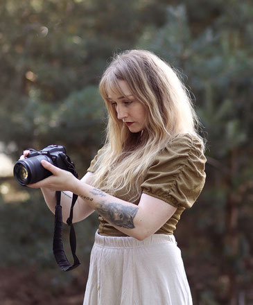 Portrait von Fotografin Malina Bura mit ihrer Kamera im Wald in der Altmark