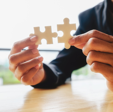 Hands connecting two pieces of a puzzle