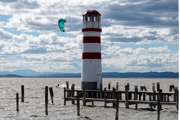Der Leuchturm in Podersdorf am See. Im Hintergrund ein Kitesurfer
