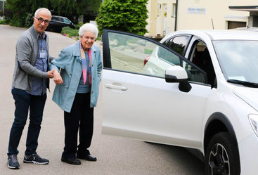 Ein Fahrer hilft einer älteren Frau beim Einsteigen