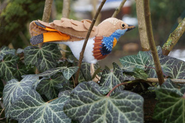 Kleiner in Handarbeit aus Filz hergestellter , dreidimensionaler Vogel , dem Blaukehlchen nachempfunden und in freier Natur fotografiert.