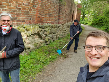 Robert Drews (r.) säubert mit Mitgliedern und Vorstandskollegen den Grünstreifen entlang der Stadtmauer.