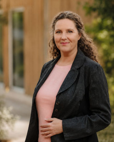 Susanne Kruse, Beraterin für Führungsübergabe in Familienunternehmen, steht in dunklem Blazer vor einer Holzfassade.