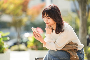 自宅のソファからスマートフォンを見る女性