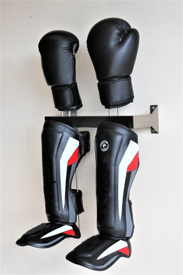 Black holder for boxing gloves and shin guards screwed to a brick wall