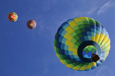 Ein Heißluftballon schließt zu zwei weiteren Ballons am Himmel auf
