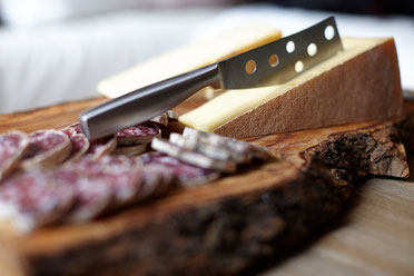 Atelier dégustation en pleine conscience au Pertuis – Planche de charcuterie et fromage sur bois brut, illustrant l'ancrage local et l'éveil des sens lors des séances de sophrologie de Gaëlle Pagès.