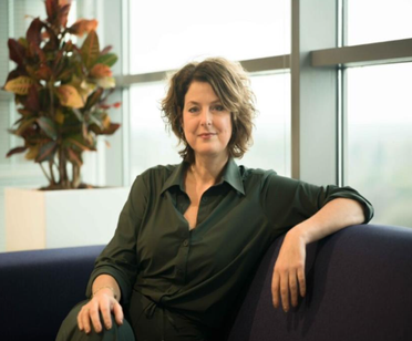 Op de foto Hester Scholten, een zelfverzekerde vrouw met halflang bruin haar in een kantoorsetting.