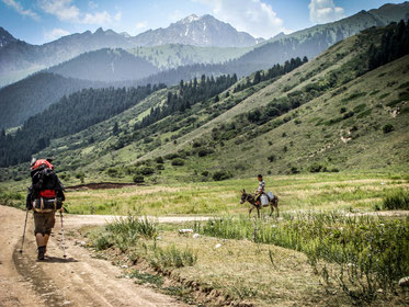 Rich nature of Kyrgyzstan and inhabitants. A boy gets some water from a river closed by.