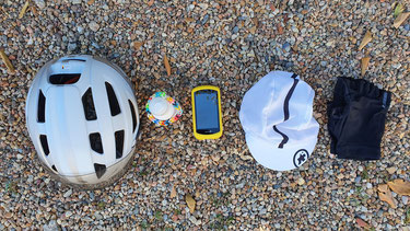 Fünf unentbehrliche Helfer auf meiner Tour - Fahrradhelm, Sonnenschutzspray, Navi, Unterziehkäppi, Fahrradhandschuhe und natürlich Toni.