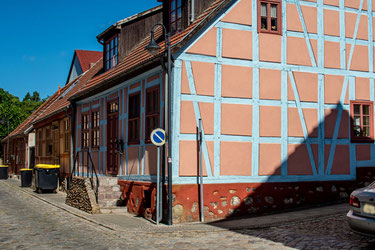 Schön restaurierte Fachwerkhäuser stehen an einer mit grobem Pflaster versehen Straße in einer historischen Altstadt.