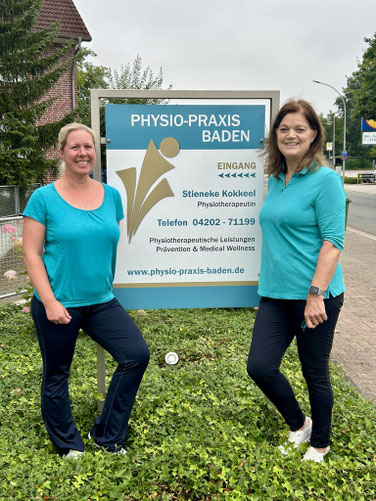 Foto der beiden Inhaberinnen Wiebke Langer-Schröder und Stieneke Kokkeel der Physio-Praxis baden vor dem Firmenschild an der Straße.