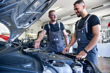 Zwei Mechatroniker blicken in den Motorraum